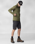 men wearing green fleece jacket and black bermudas putting things in his pocket