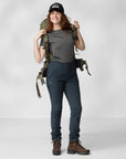 woman in grey top and blue trekking trousers carrying a trekking backpack