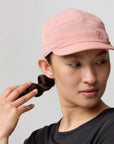 Person wearing a pink cap with a Fjällräven logo on a plain background