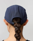 Person wearing a blue cap with a braid on a plain background