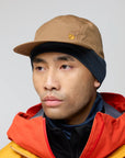 Person wearing a brown cap and colorful jacket on a plain background