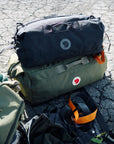 Two backpacks on a cracked asphalt surface with visible Fjällräven logos.