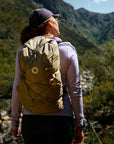 Person with a beige backpack looking at a mountainous landscape