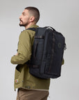 Man wearing a black backpack on a plain background
