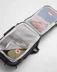 Open backpack with clothes inside on a light gray background