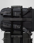 Black travel backpack and suitcase stacked on a light gray background
