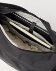 Black duffel bag with a laptop and clothes inside on a white background