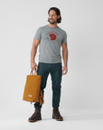 man in grey melange round neck t-shirt and blue trekking trousers carrying a orange bag
