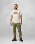 man wearing white round neck t-shirt with Fjällräven logo and green trousers