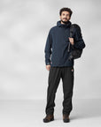 man in navy windbreaker jacket with hoodand black long pants