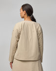 Woman wearing a beige outfit against a gray background