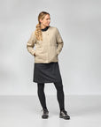 Woman wearing a beige jacket, black skirt, and leggings on a white background