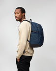 Man wearing a blue backpack on a plain background