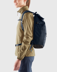 woman carrying navy foldtop backpack