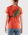 woman with green waist bag with a visible Fjällräven logo