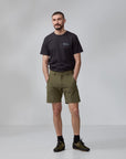 Man wearing a black t-shirt and green shorts on a gray background