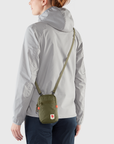 woman carrying a green small sling bag