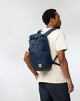 man carrying navy backpack with rolltop