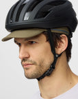Person wearing a black helmet and beige cap on a light gray background