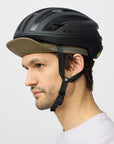 Person wearing a black helmet with a green cap on a white background