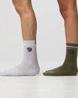 White and green socks with a fjallraven logo worn by a person on a light gray background