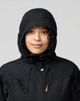 Person wearing a black hooded jacket on a gray background
