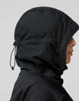 Person wearing a black hooded jacket on a light gray background
