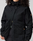 Person wearing a black jacket with a fjallraven logo on a gray background