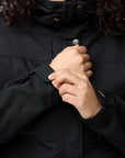 Person wearing a black jacket with hands clasped in front