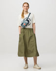 Person wearing a graphic t-shirt and green skirt on a white background