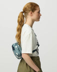 Woman wearing a white t-shirt with text and a blue patterned backpack on a light gray background