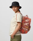 Person wearing a white t-shirt, black bucket hat, and carrying a red camouflage backpack on a light gray background