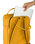 Yellow backpack with a hand placing a white laptop into it on a white background