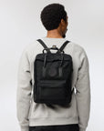 man carrying a kanken black backpack