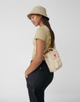woman carrying a white sling bag with Fjällräven Kånken logo
