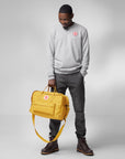 man carrying yellow Fjällräven logo duffel bag