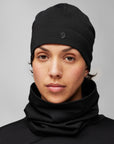 Person wearing a black beanie and scarf against a gray background