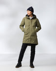 Person wearing a green coat, black pants, and a black beanie on a white background
