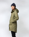 Person wearing a green parka and black beanie on a white background