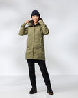 Person wearing a green coat, black pants, and a black beanie on a white background