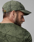Man wearing a camouflage cap and shirt against a gray background