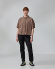 Person wearing a brown short-sleeve shirt and black pants on a plain background