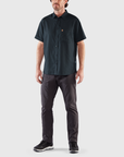 man wearing navy button collared shirt and black trousers