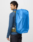 Person wearing a blue backpack cover on a plain background
