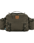 A green Fjallraven Singi Hip Pack 10 bag with a visible arctic fox logo, zippers, and a shoulder strap.