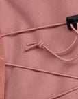 Close-up of a pink backpack with a drawstring and black clip.