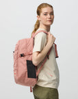 Person wearing a pink backpack on a light gray background