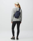 Person wearing a gray sweatshirt and black leggings with a navy crossbody bag on a white background