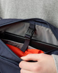 Person opening a navy blue backpack with a gray interior.