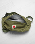 green sling bag with Fjällräven logo and opened zip